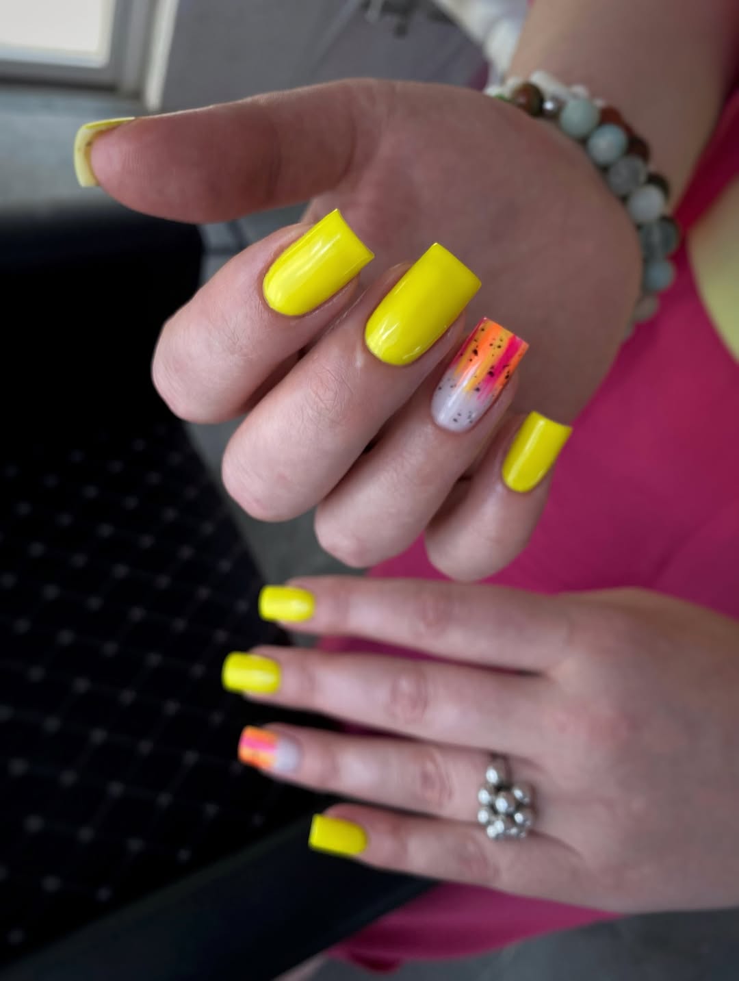 Vibrant Yellow Nails with Neon Speckled Accent