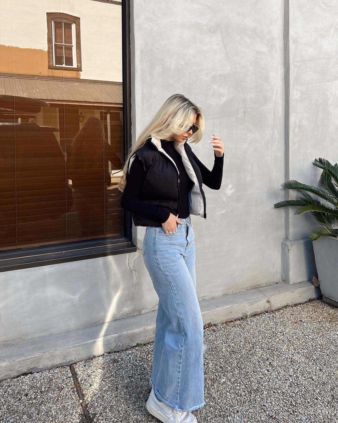 Black Puffer Vest Over Black Turtleneck With Wide Leg Jeans
