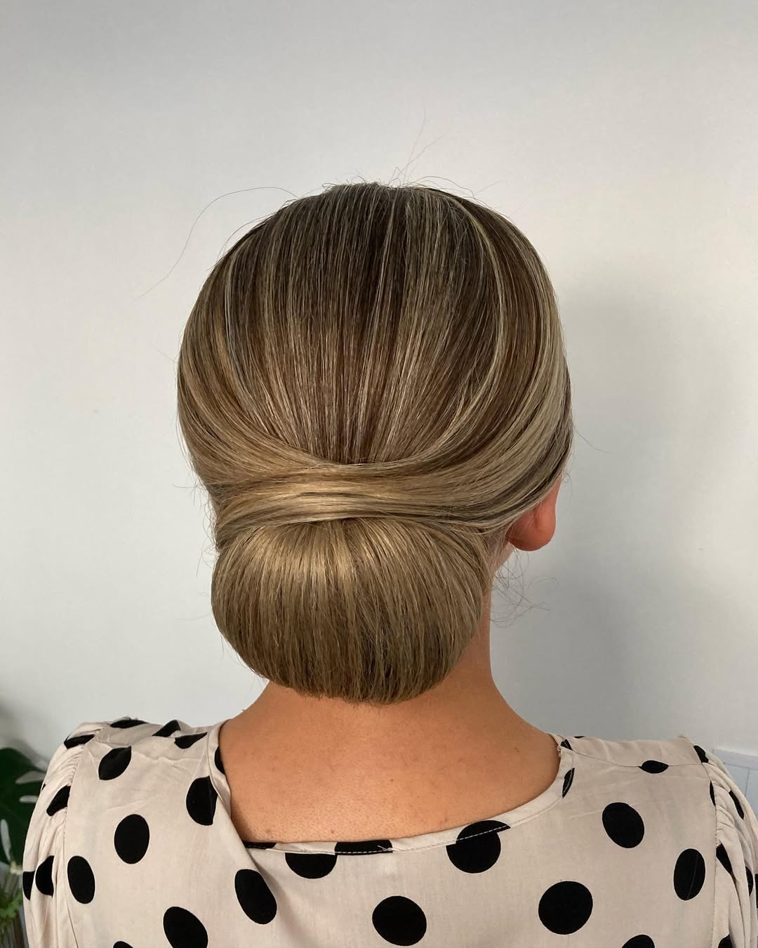 Sleek Low Bun With Face-Framing Blonde Highlights