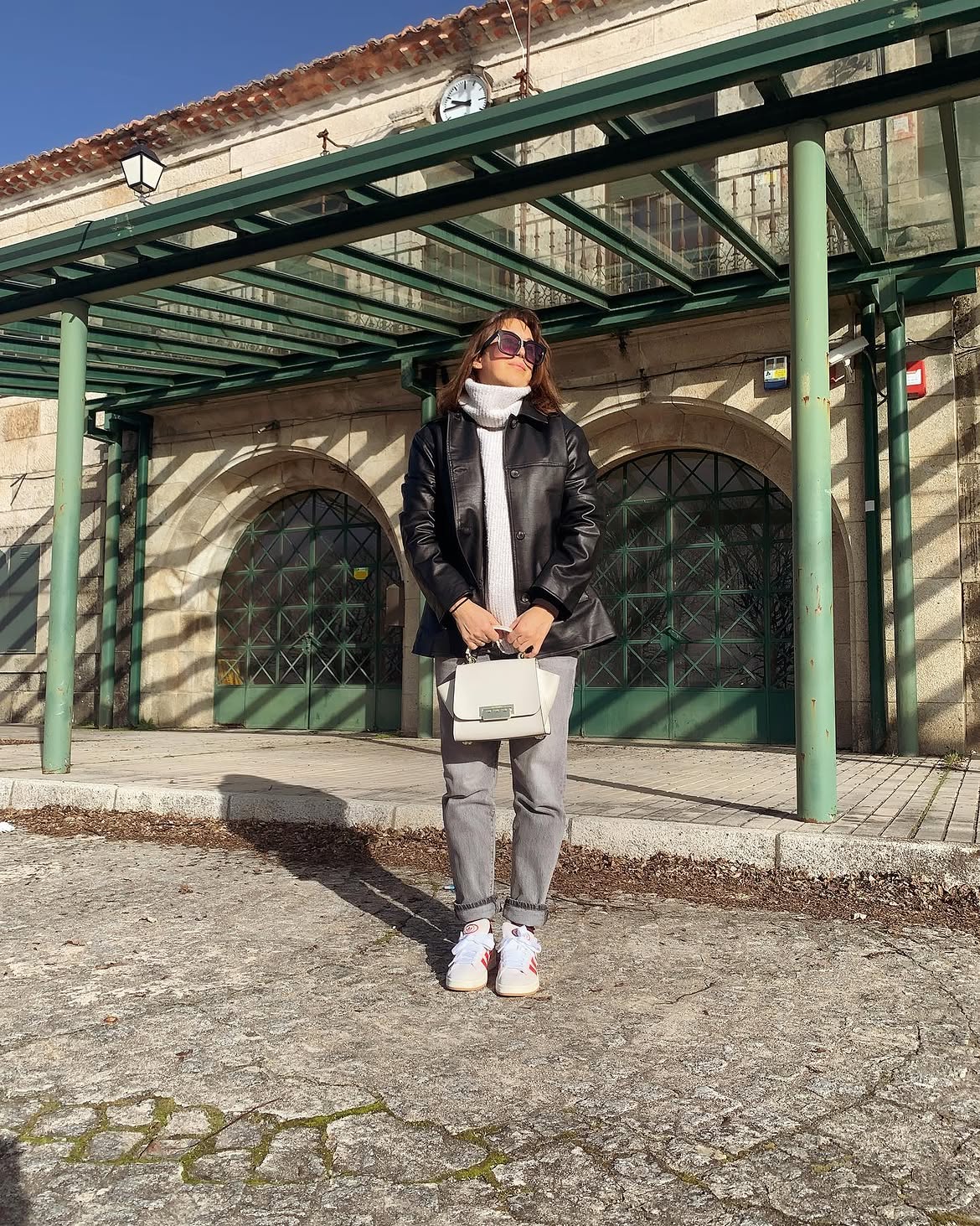 Black Faux Leather Jacket Over White Turtleneck And Grey Denim